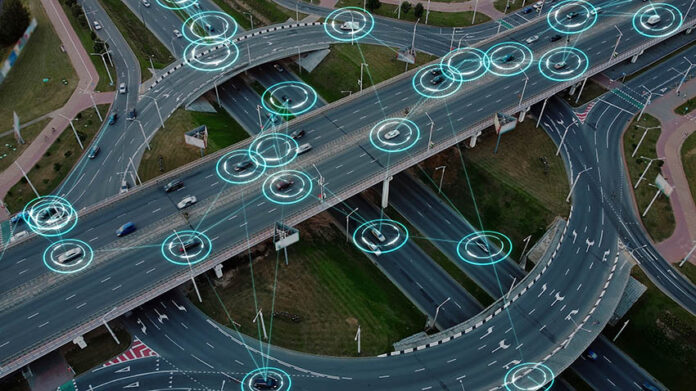 Vista aérea: Los vehículos eléctricos autónomos del futuro con elementos HUD se mueven a lo largo de una intersección de tráfico muy transitada. Concepto: Inteligencia Artificial, Car Scan, Rastreo GPS, Carreteras Inteligentes, IoT.